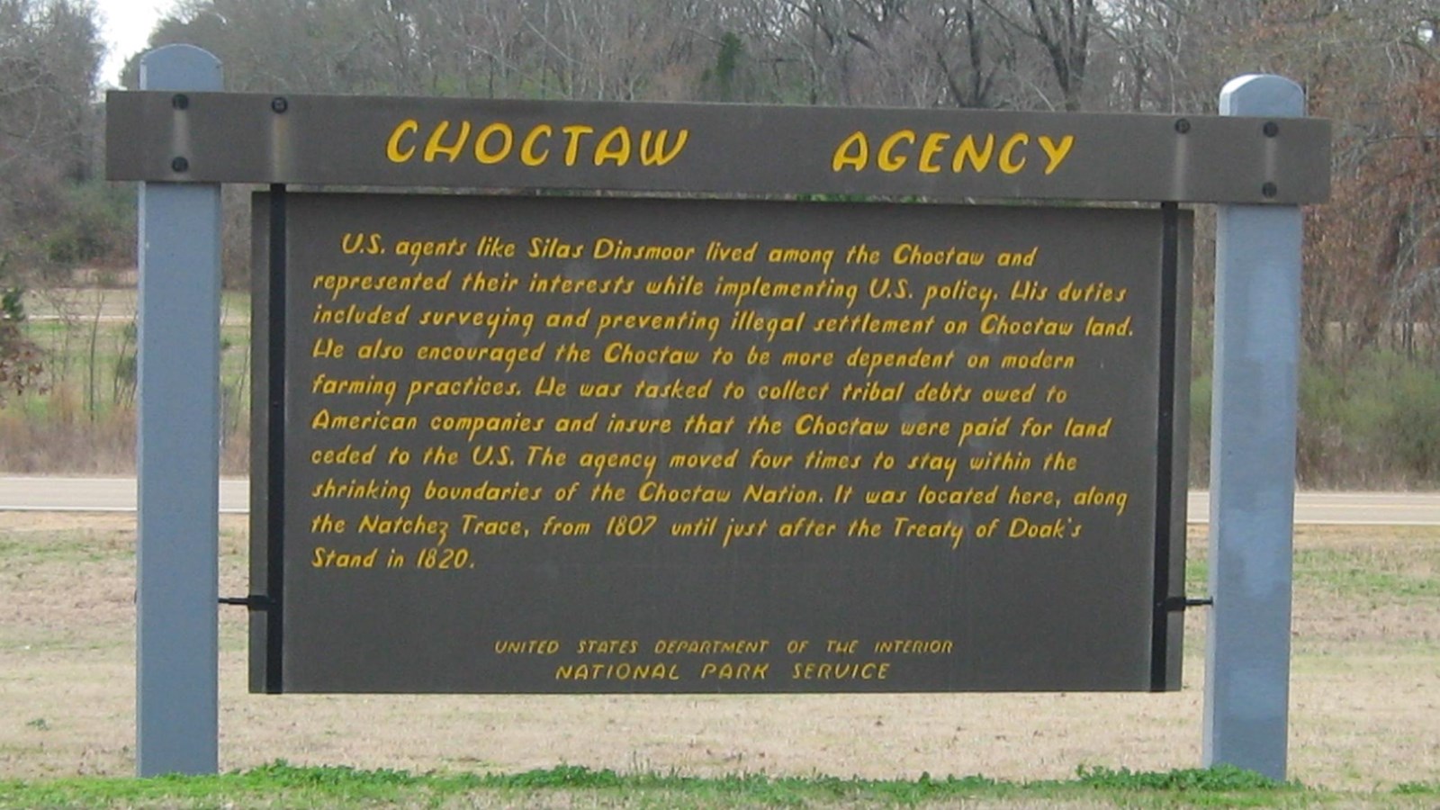 Wooden sign painted brown with yellow letters entitled 
