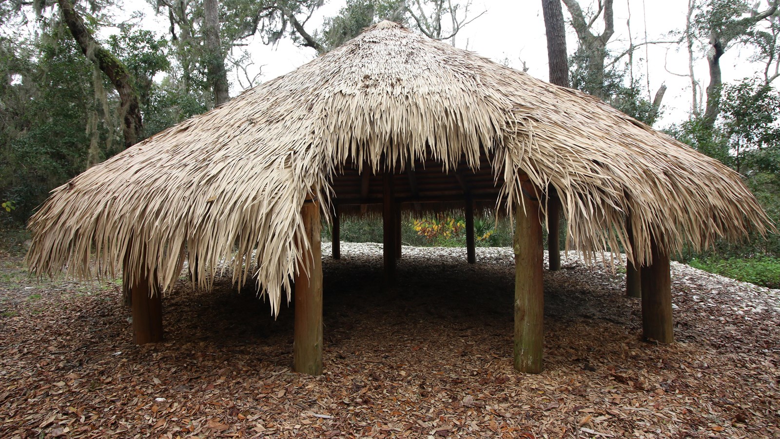 a round structure with open sides and a palm thatched roof