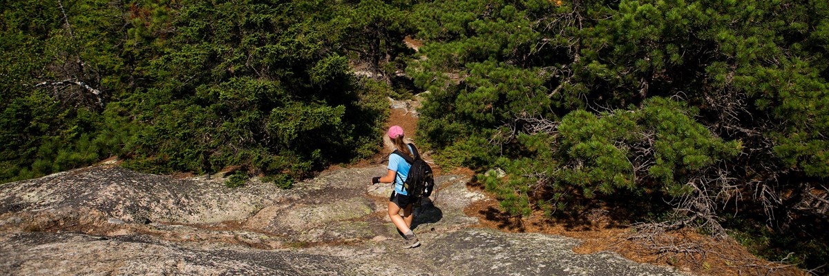 Visitor hikes down exposed granite section of trail