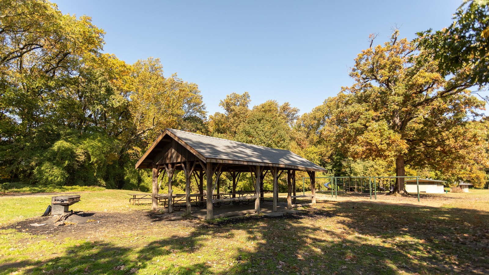 A covered picnic table in a grassy field surrounded by trees. 