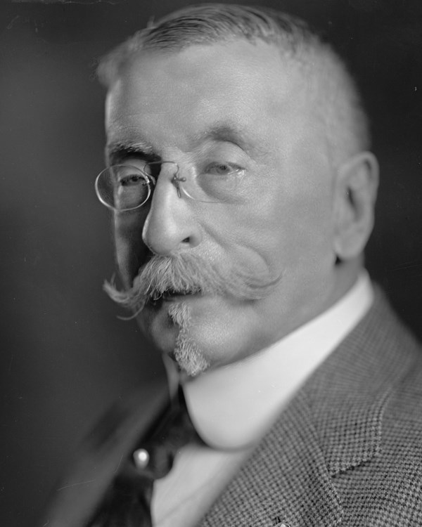 An early 1900s portrait photo of a well dressed older man with pince-nez spectacles.