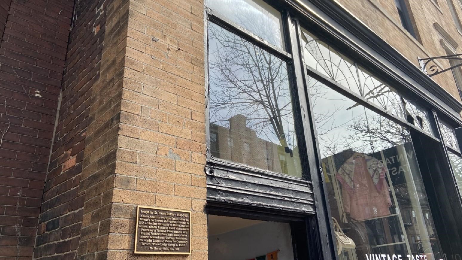 Charles Street brick townhouse with historical plaque and large window storefront.