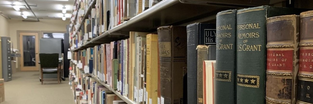 Library shelves in a basement room stacked with books across the shelves.