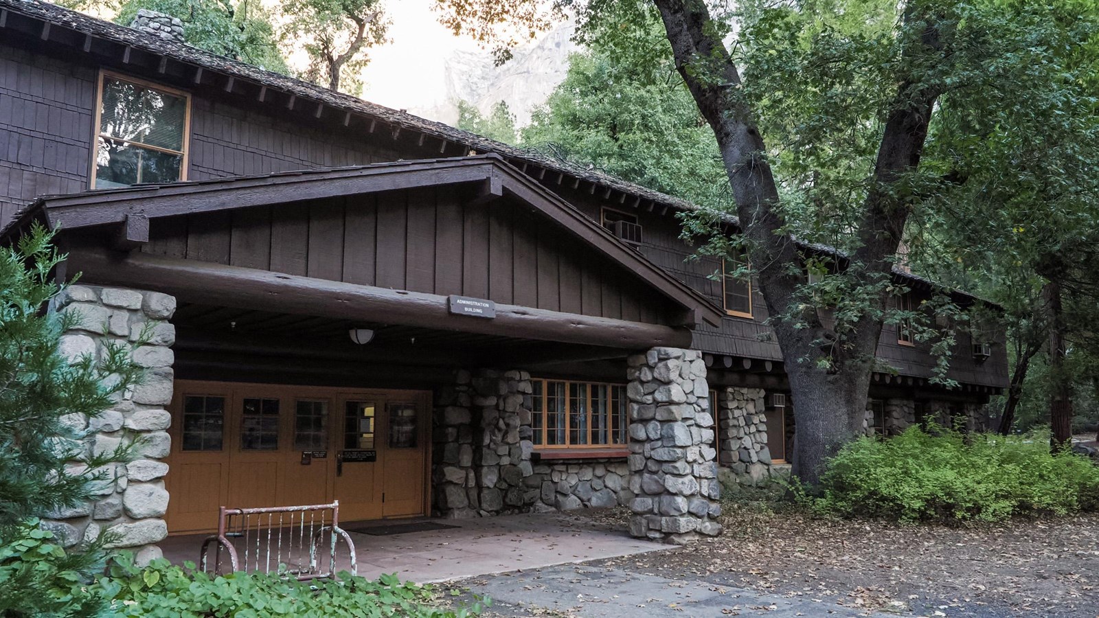 A covered entrance to a two-story building with a stonework first level and shingled second level