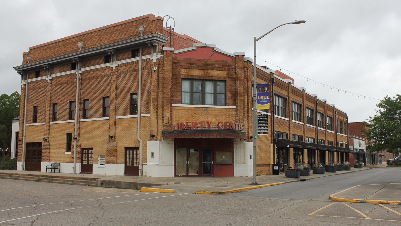 A three story brick building with a red and black awning with text 
