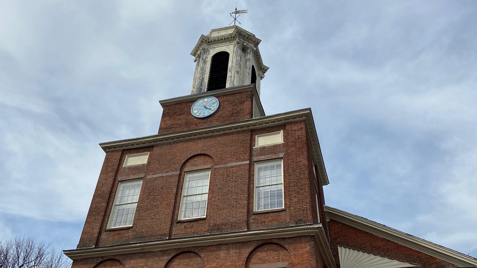 Brick facade of Charles St. Meeting House with white steeple.