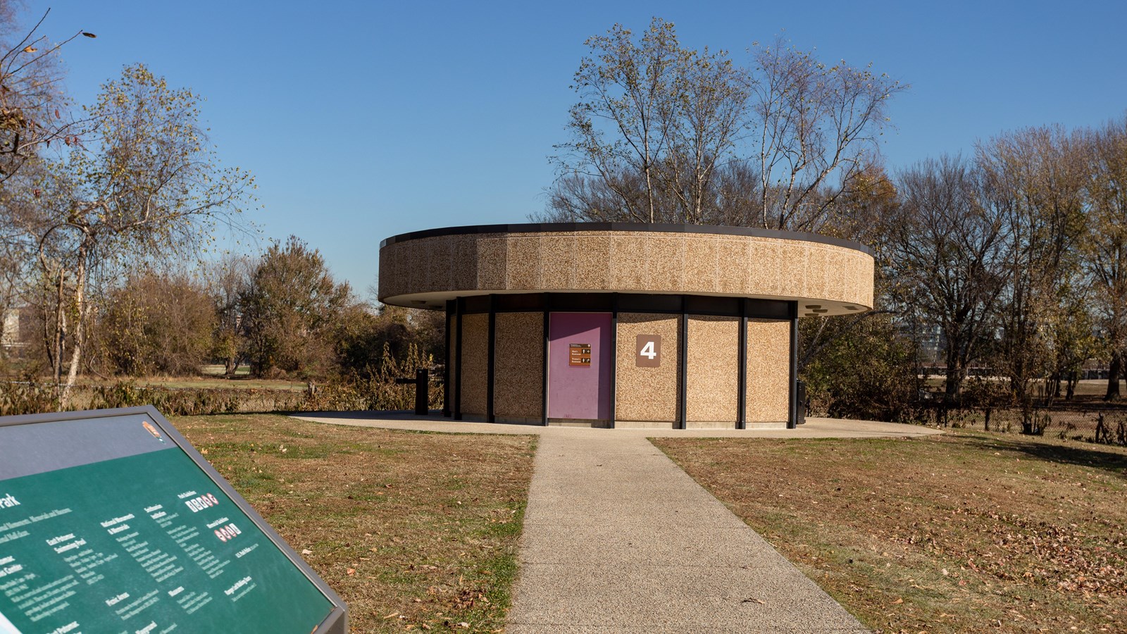 A circular restroom building at the end of a sidewalk.