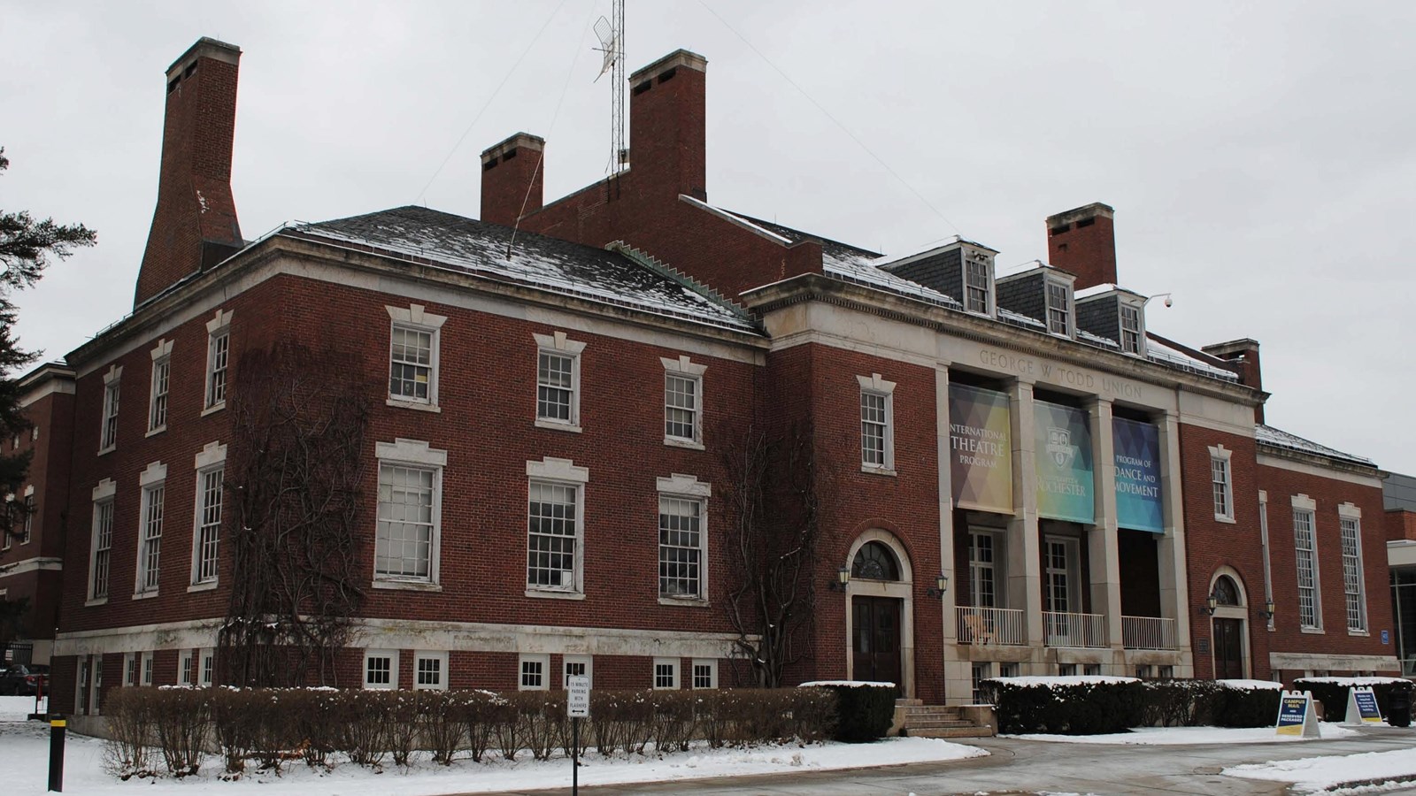 Three-story red brick building with multi-colored banners advertising theatre and dance program