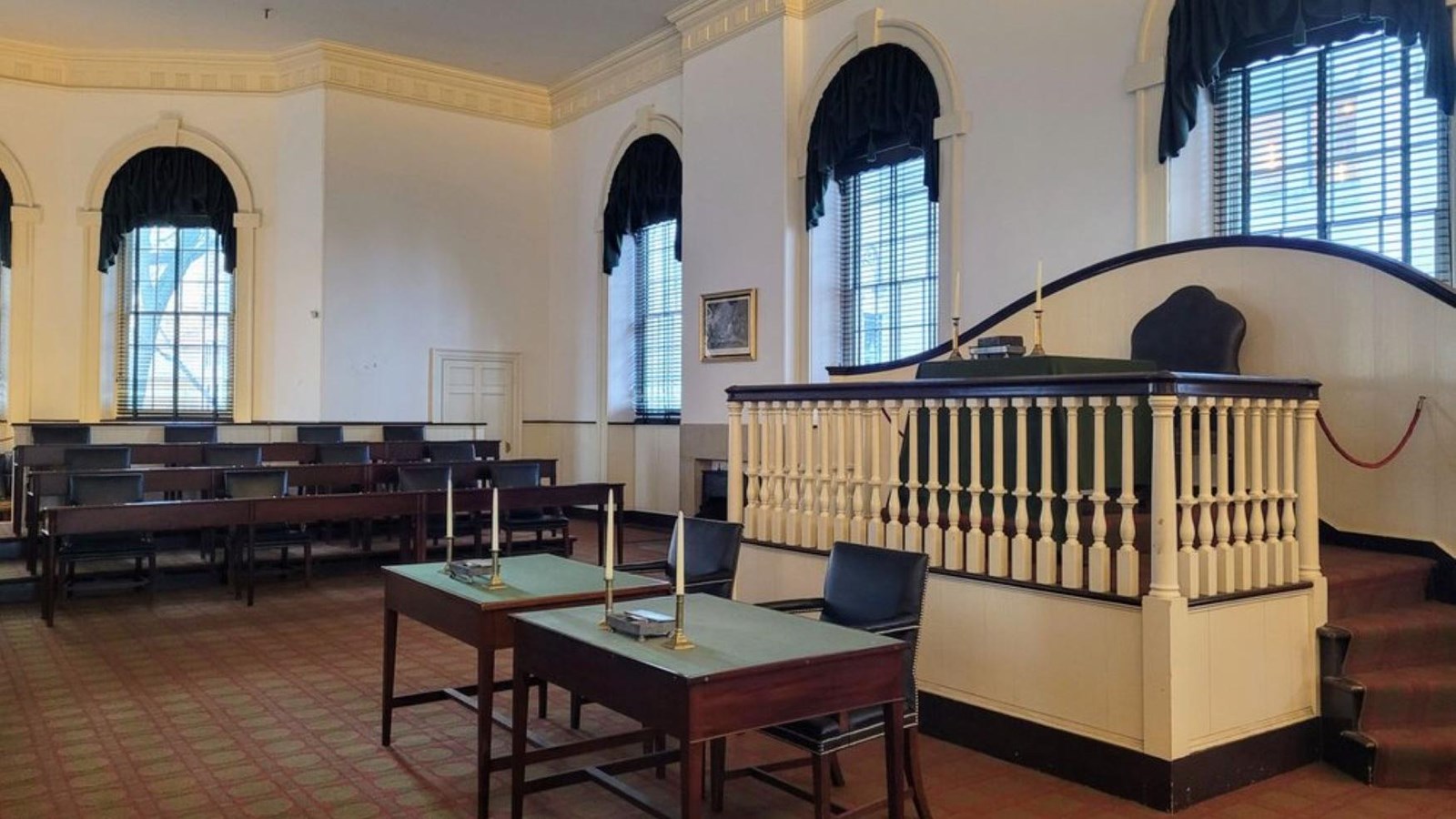 A platform with a large chair and desk. Two chairs and desks in front