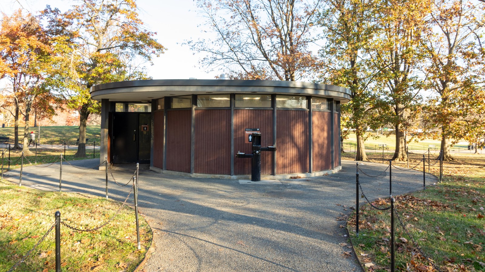 A circular restroom building at the end of a sidewalk.