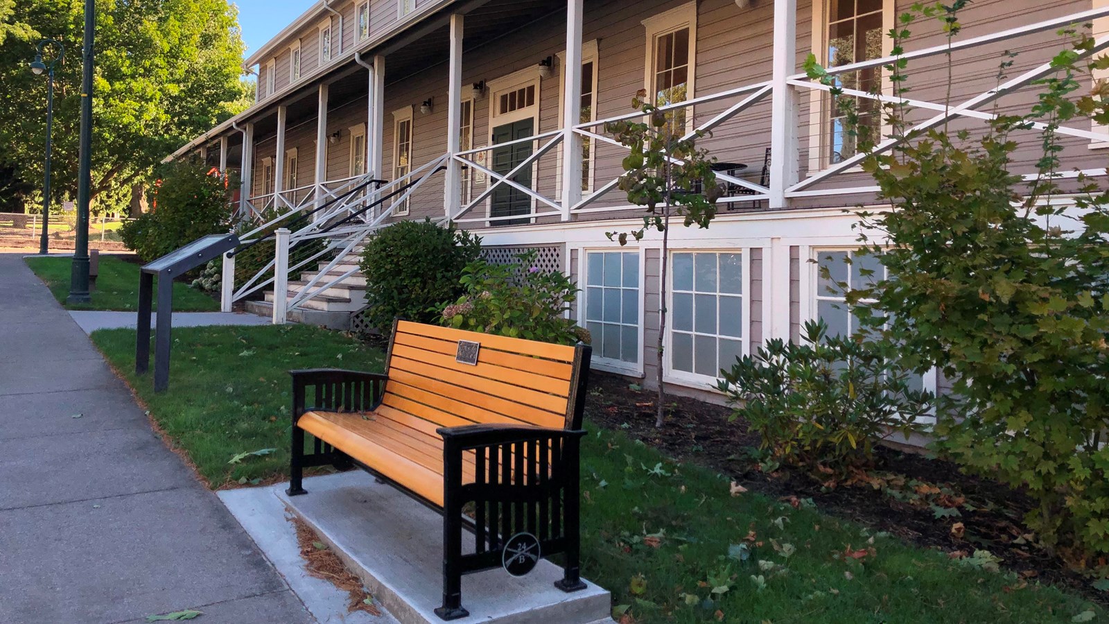 A grey two story building with a bench in front of it.