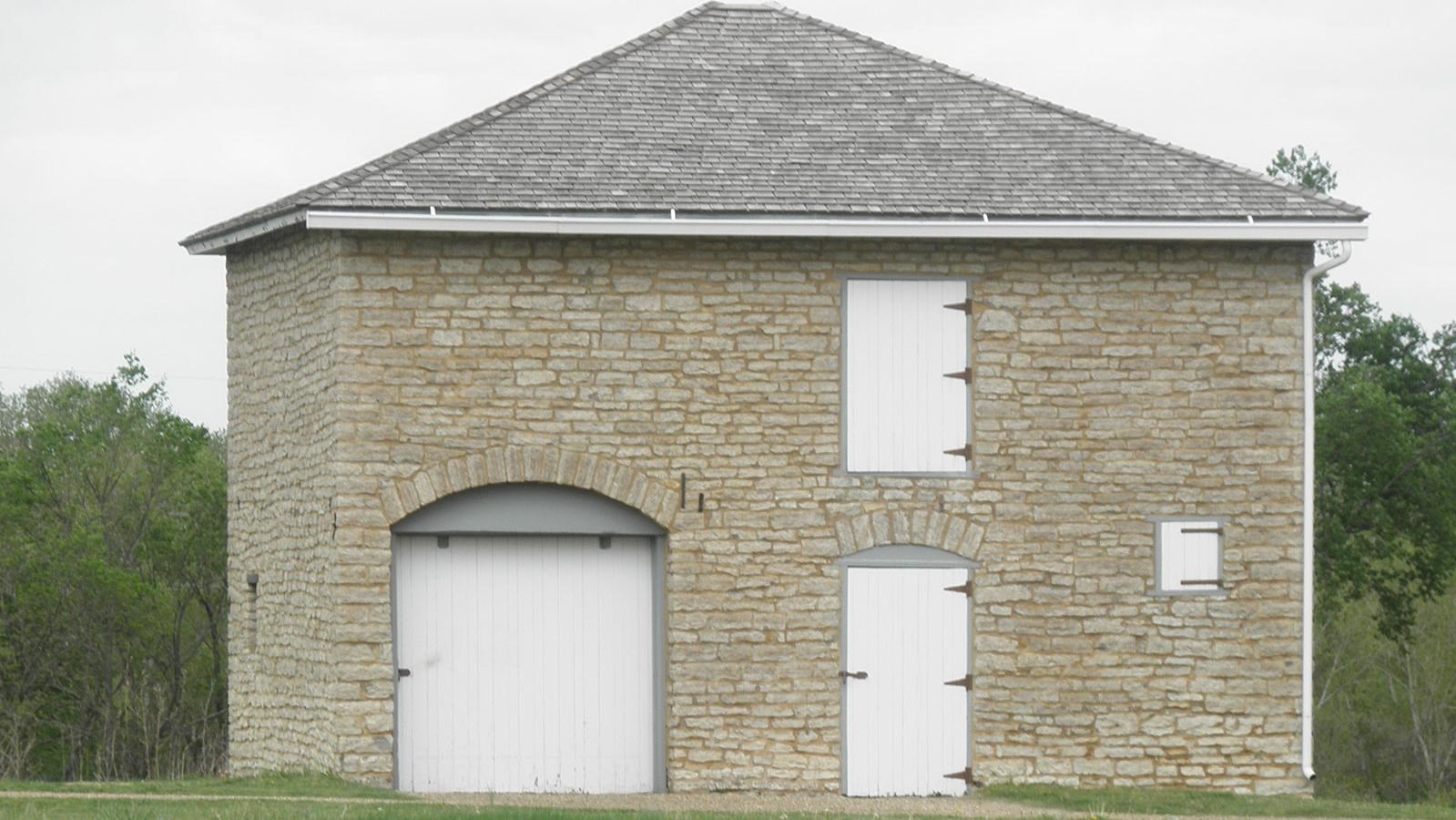 tall stone buiding with roof, two doors, and a window