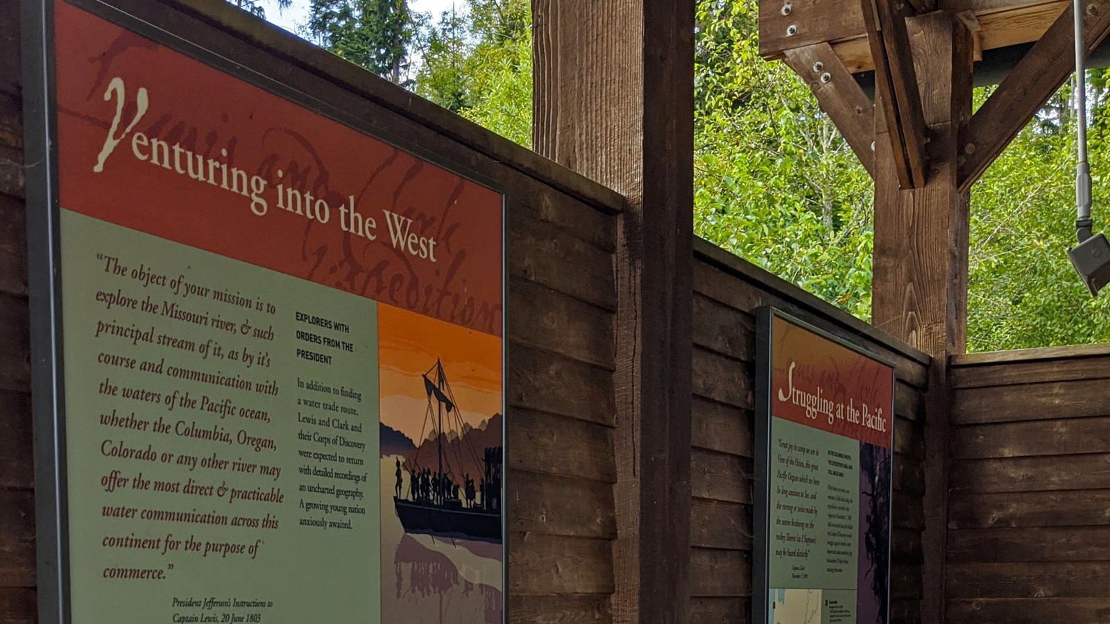 Wooden plank walls support two signs, each divided into four sections with pictures, text, and maps.