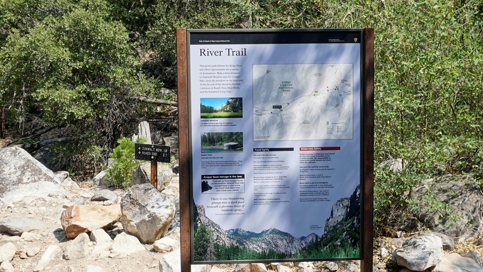 A metal panel has text and images on it with information about the river trail