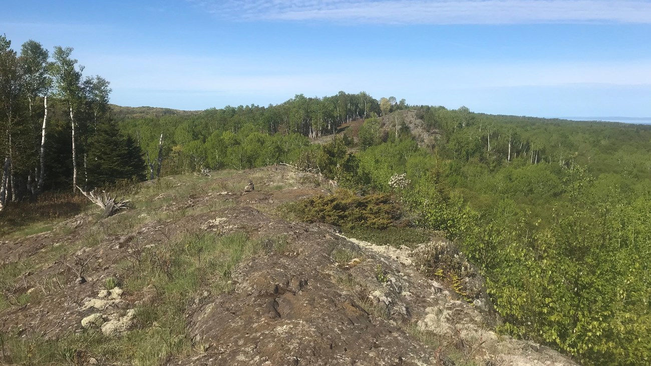 The trail crosses an exposed rocky ridge surrounded by forest. 