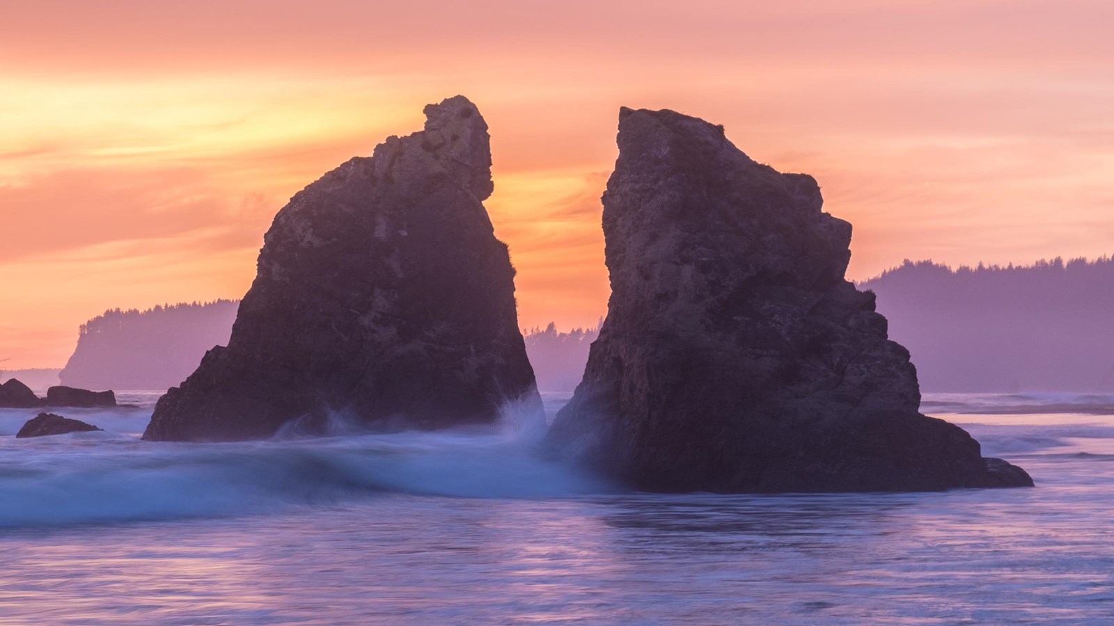 Sunset at a beach with rocky sea stacks and lavender water