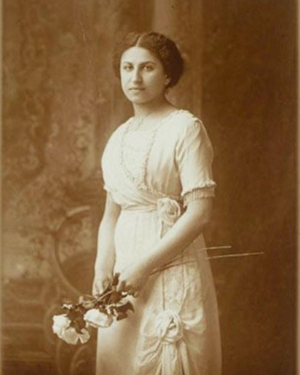 Portrait of a woman with her hair pulled back, wearing a white dress and holding a bouquet