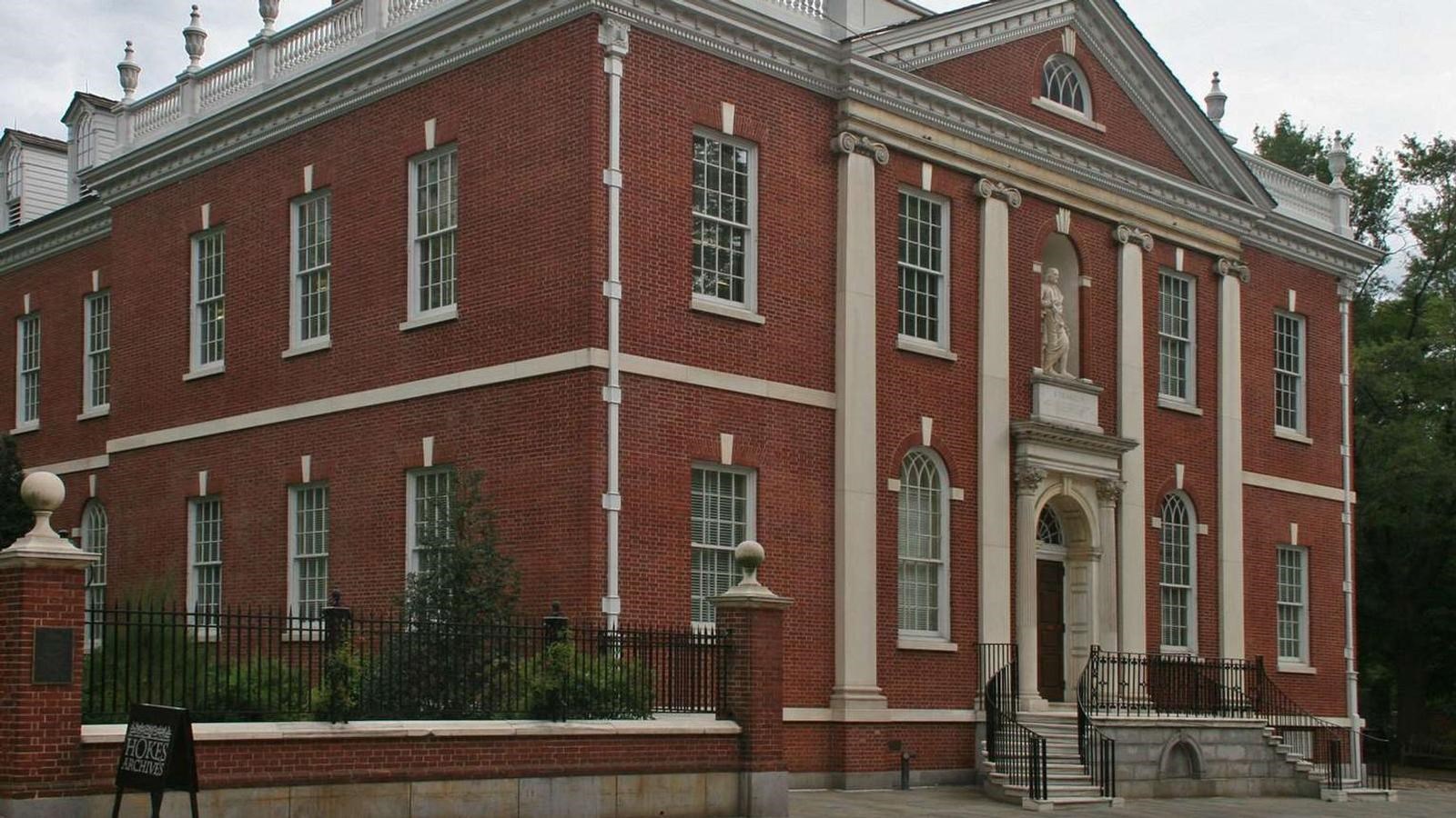 A color photo of a two story brick building with white trim and two rows of windows on each floor.