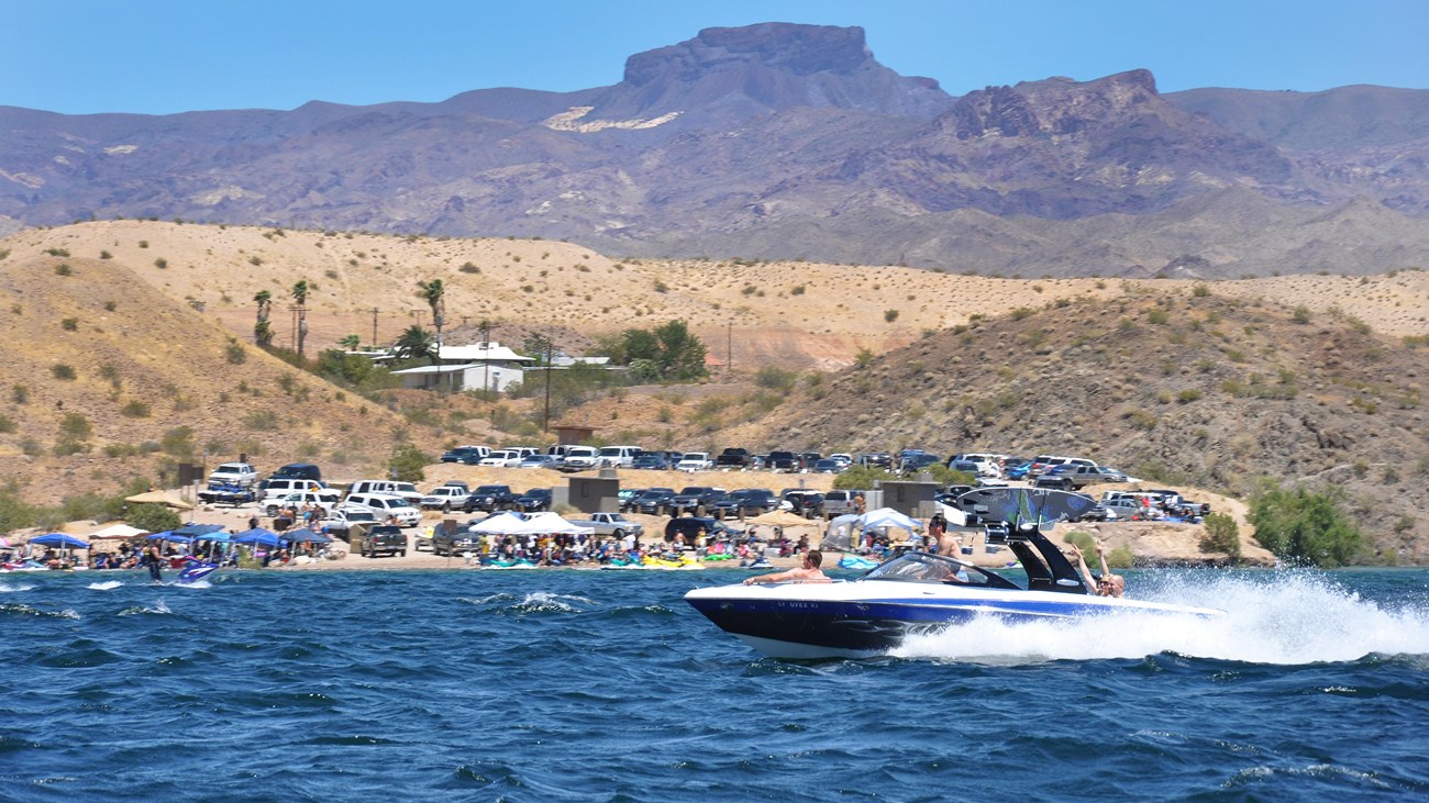 A boat on a body of water with crowds in the background