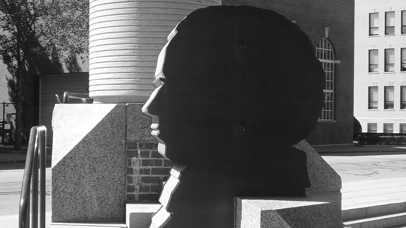 A granite and metal sculpture features the silhouette of a man\'s face.