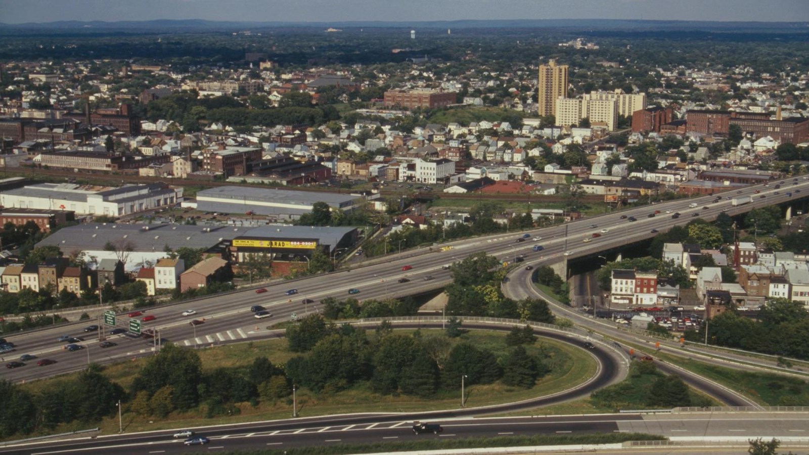Industrial buildings extend to the horizon with a highway cutting across the foreground.