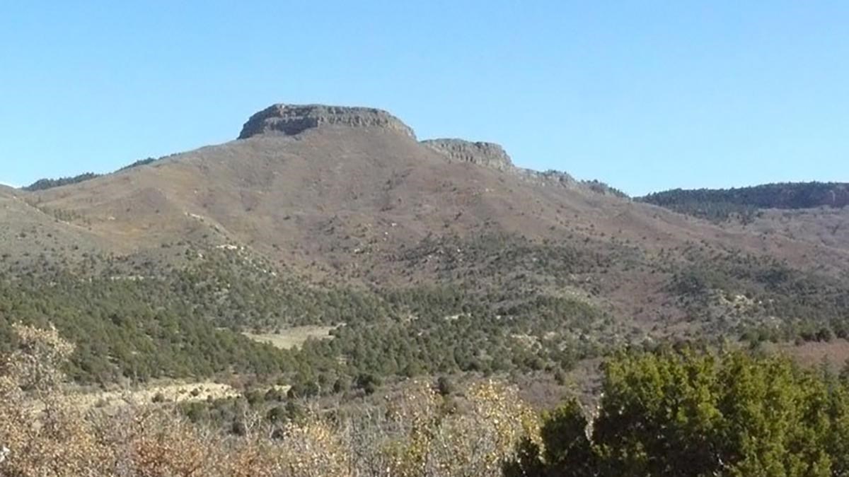 A wayside exhibit with a large butte in the distance.