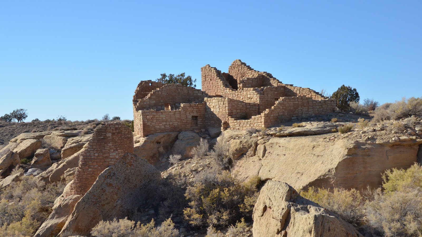 remains of several stone structures perched in and around a shallow canyon