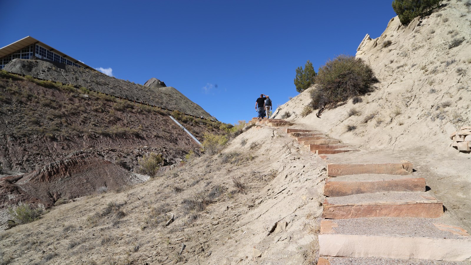 A pair of hikers walking up along stone steps through desert hillsides.