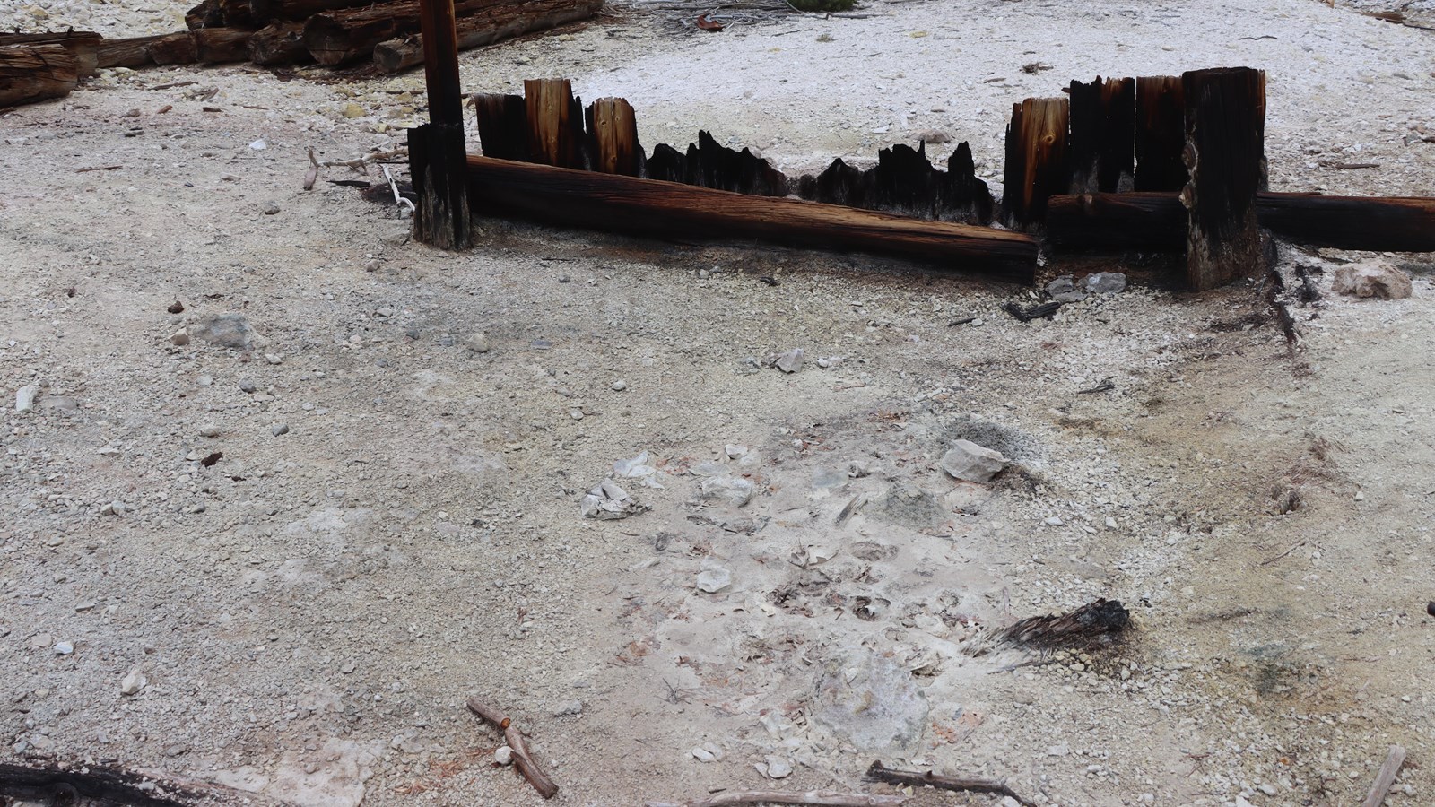 Remnants of a wooden structure near a volcanic mudpot.