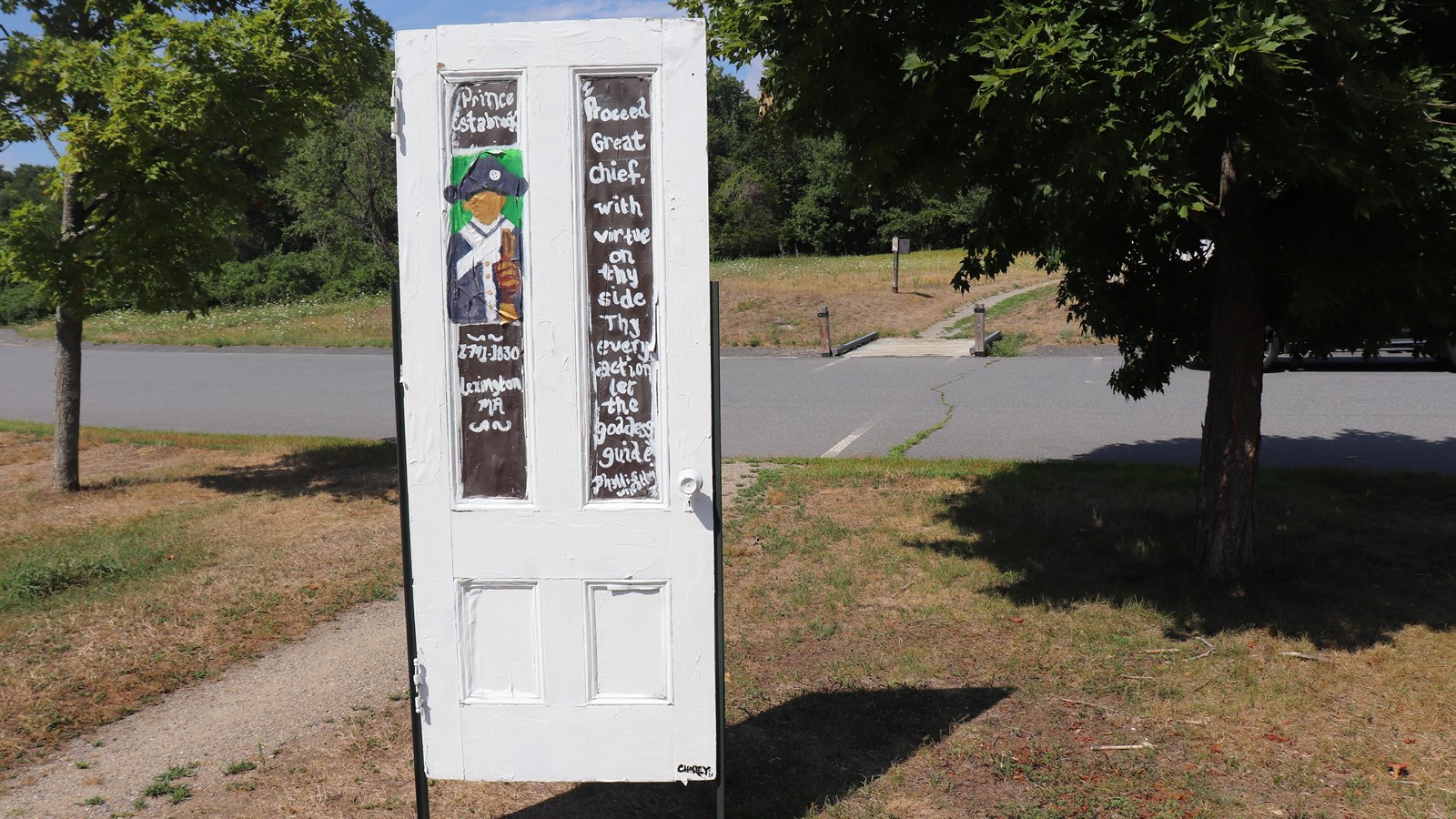 A white door is staked into the ground. The image of a black soldier is painted on the door.