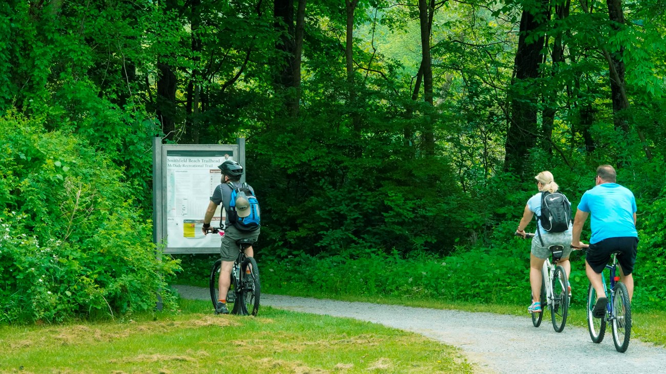 Three people bike onto the McDade Recreational Trail.