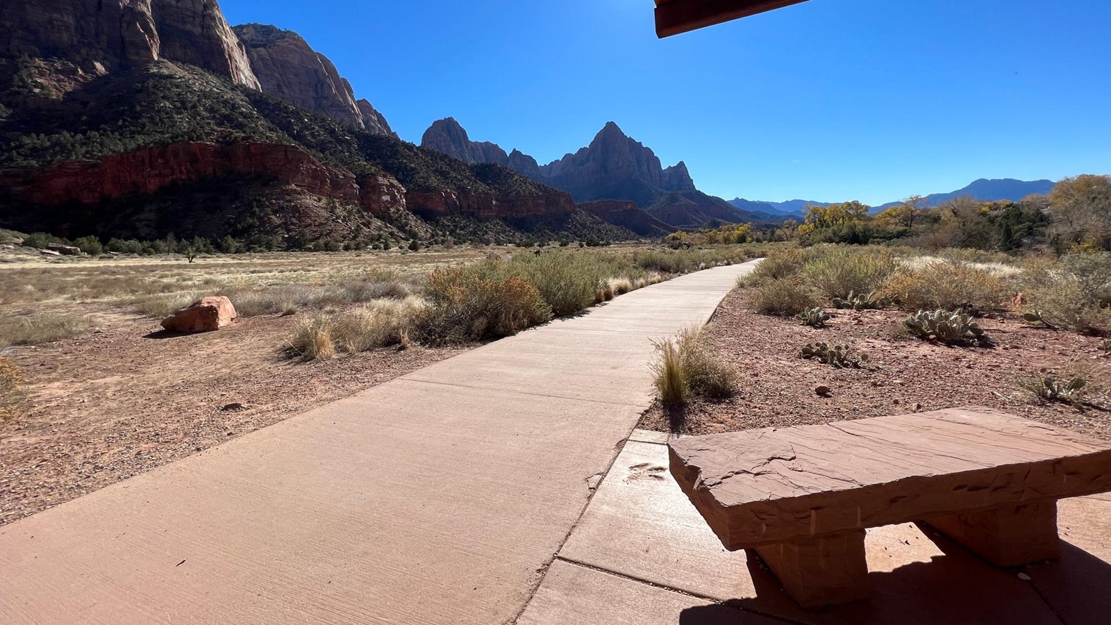 Photo looking down a paved path towards a triangular mountain.