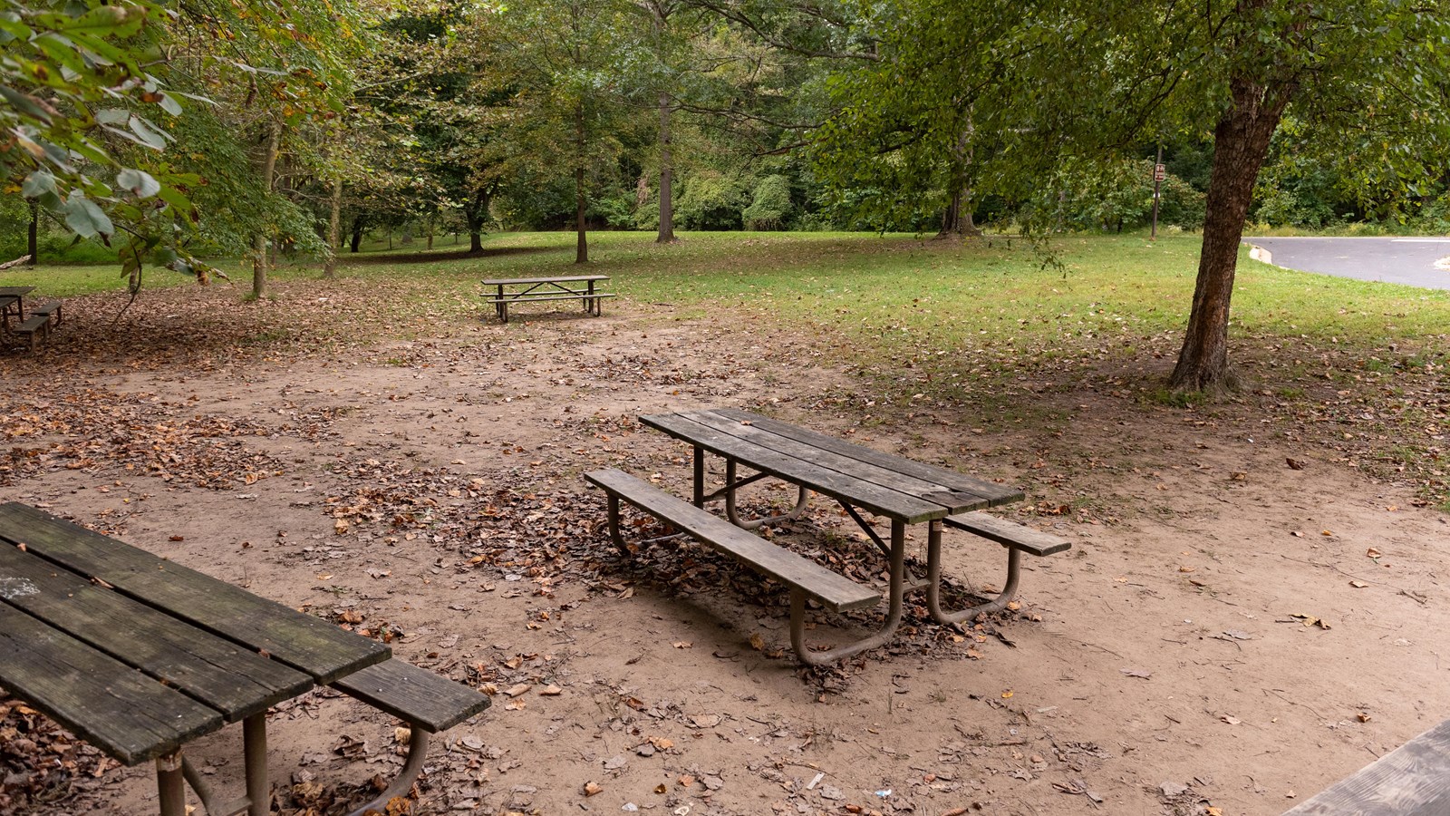 Two picnic benches in front of a grassy field. 