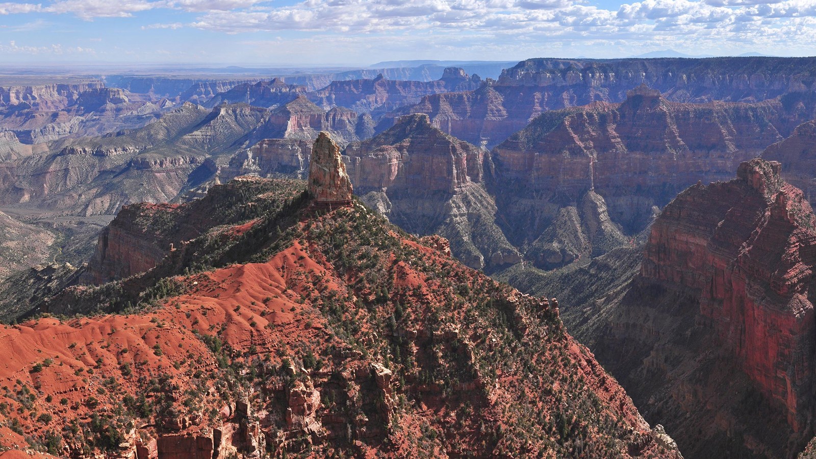 A prominent formation with a white rock spire against the backdrop of the red cliffs of Grand Canyon