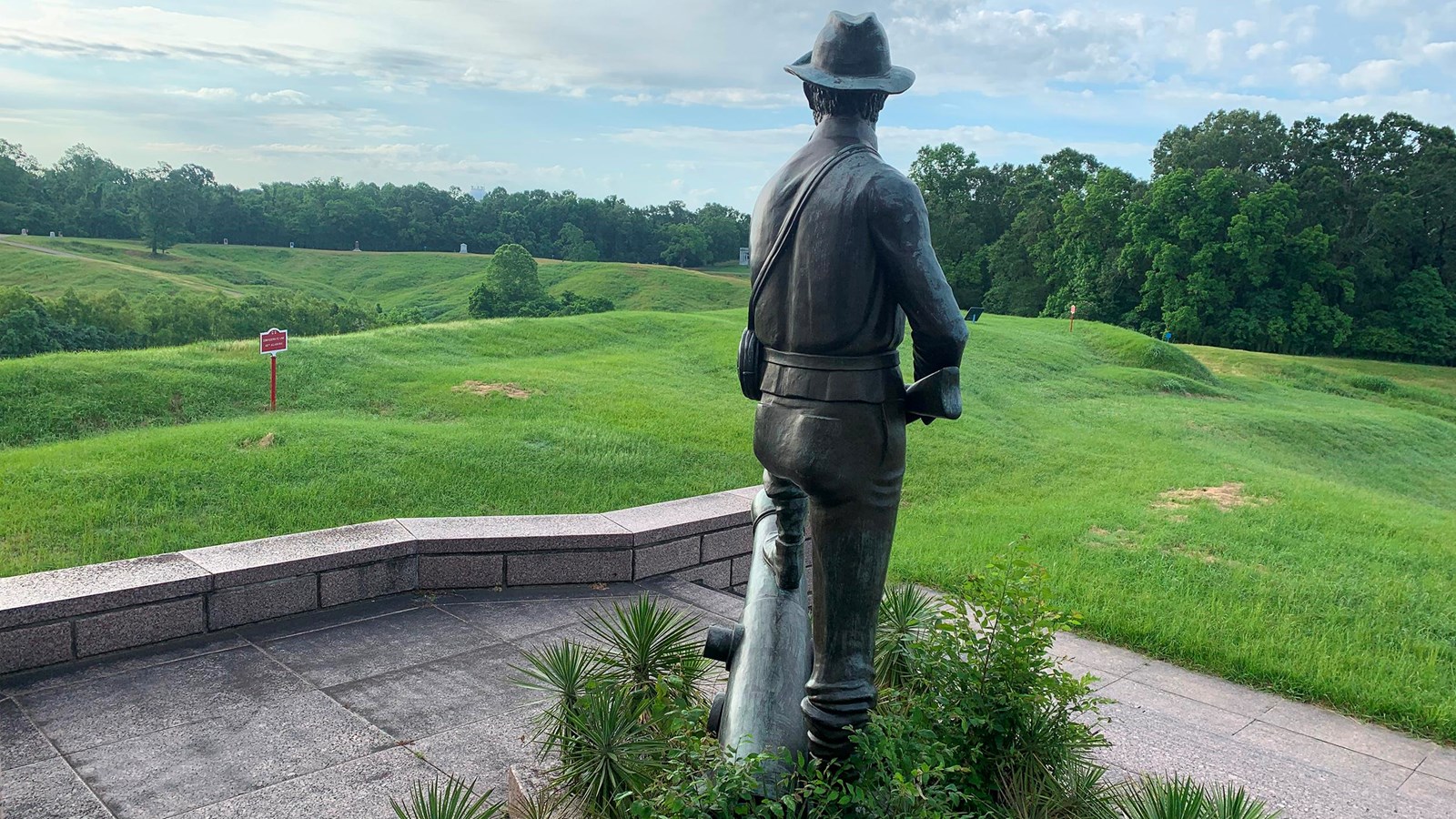 The back of a statue of a soldier holding a musket looks over the Railroad Redoubt and battlefield.