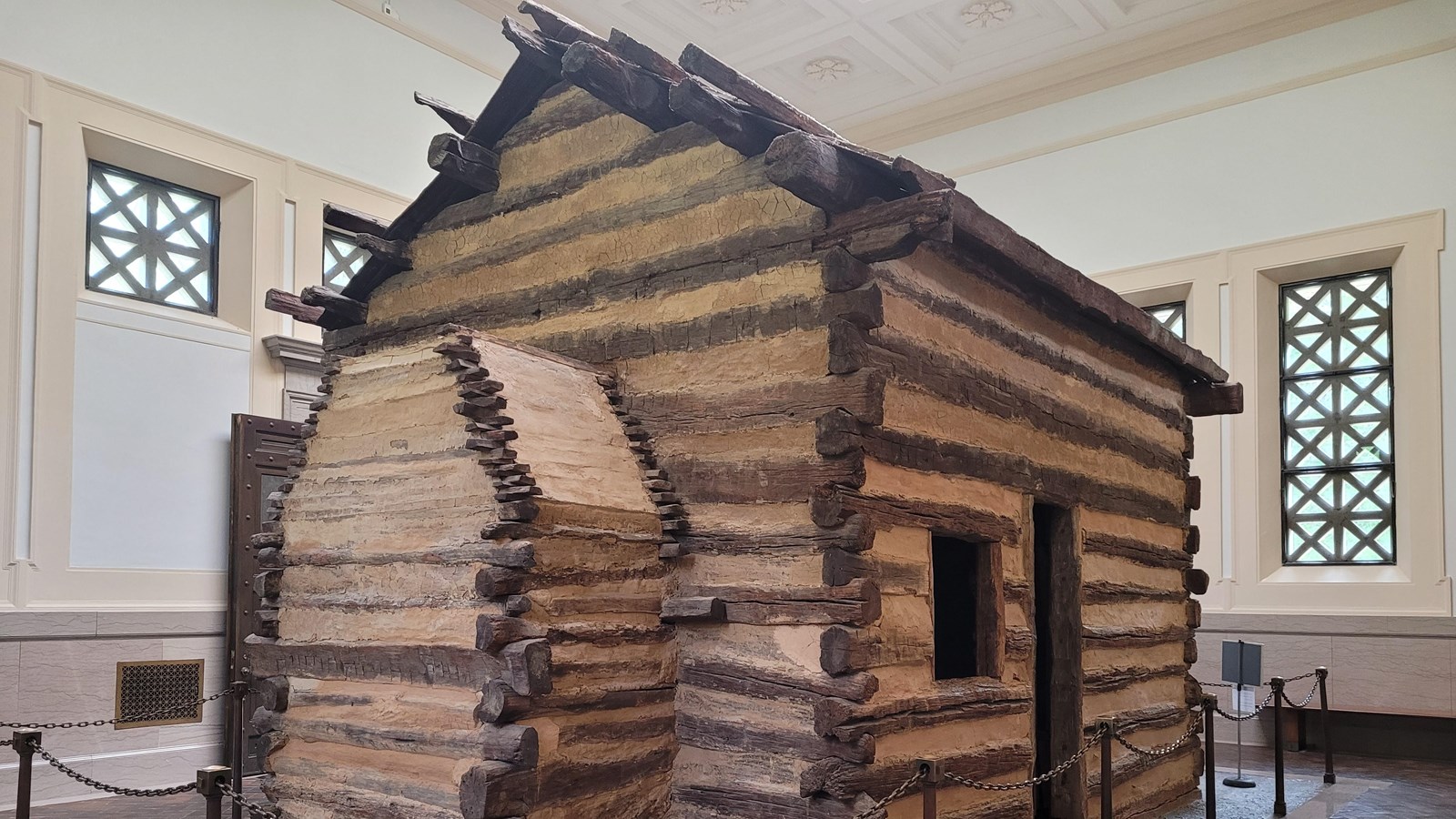 light brown log cabin with a chimney on its left that inside a building.