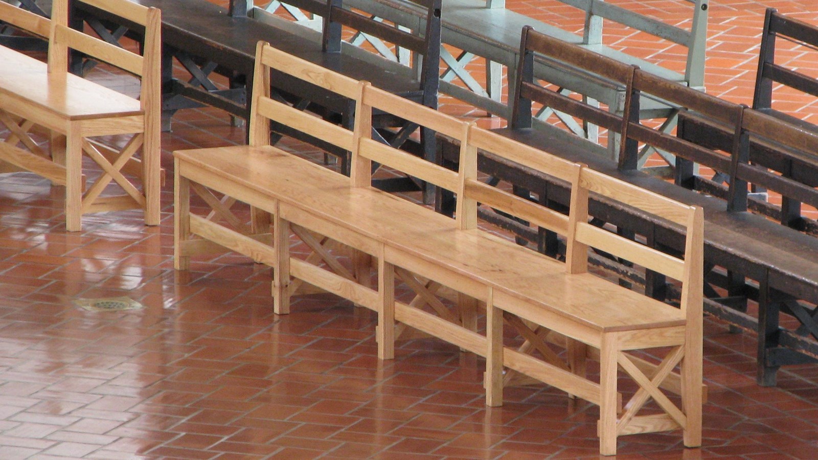 Wooden benches with backs between two pillars on a dark red floor