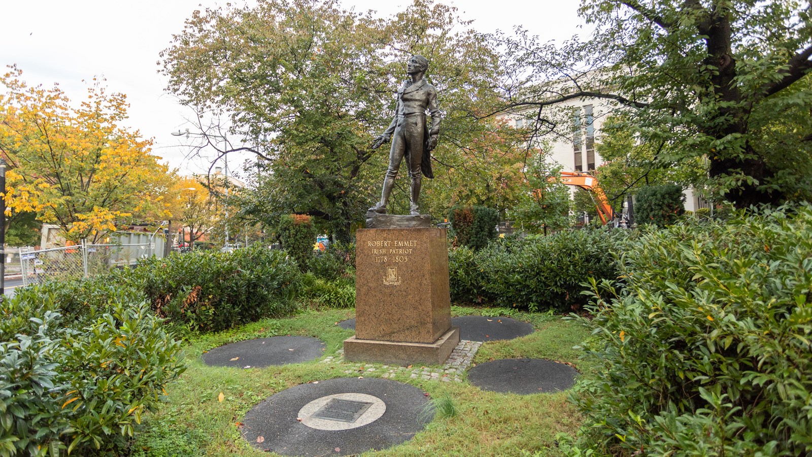 A large bronze statue on top of a stone monument in a grassy plaza