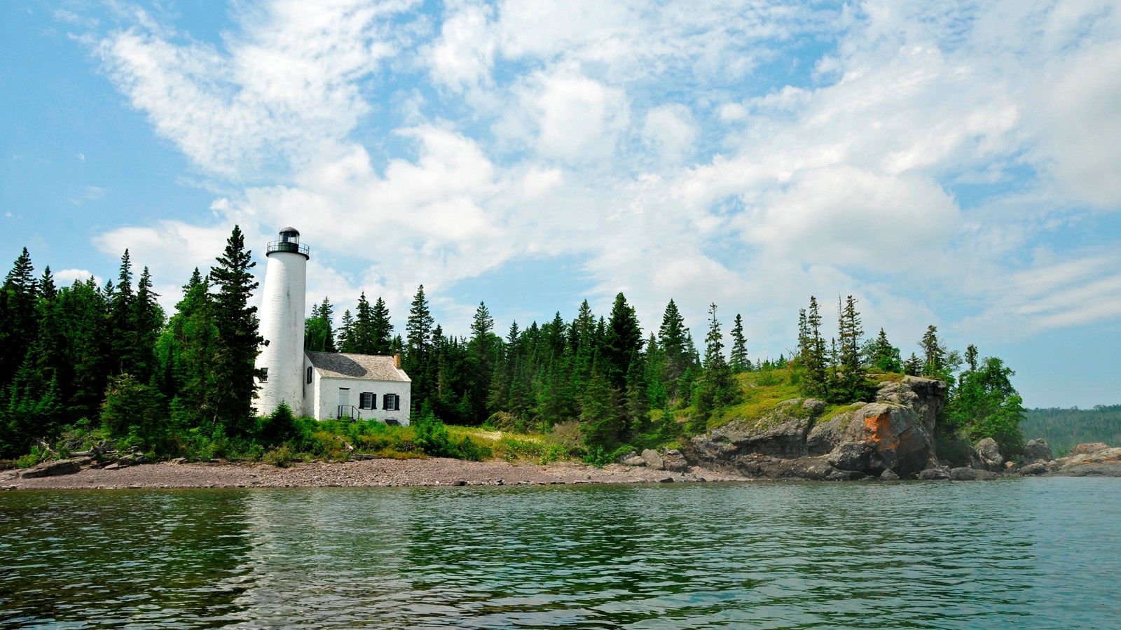 a view of the Rock Harbor Lighthouse from the waters of Middle Islands Passage on a bright blue day