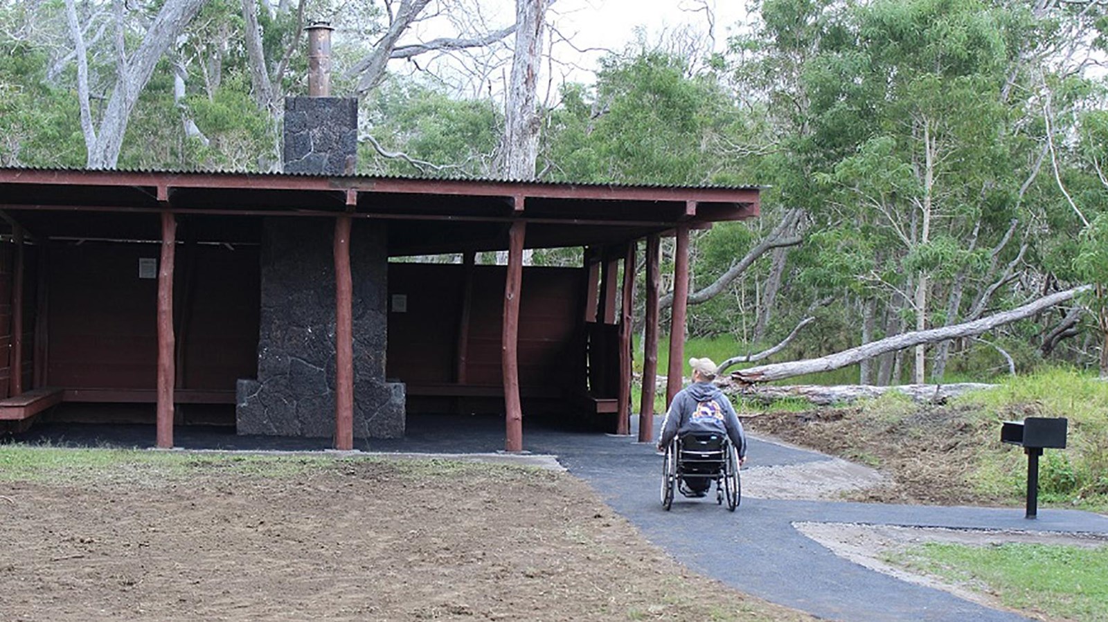 A person in a wheelchair moving toward a red three-sided shelter