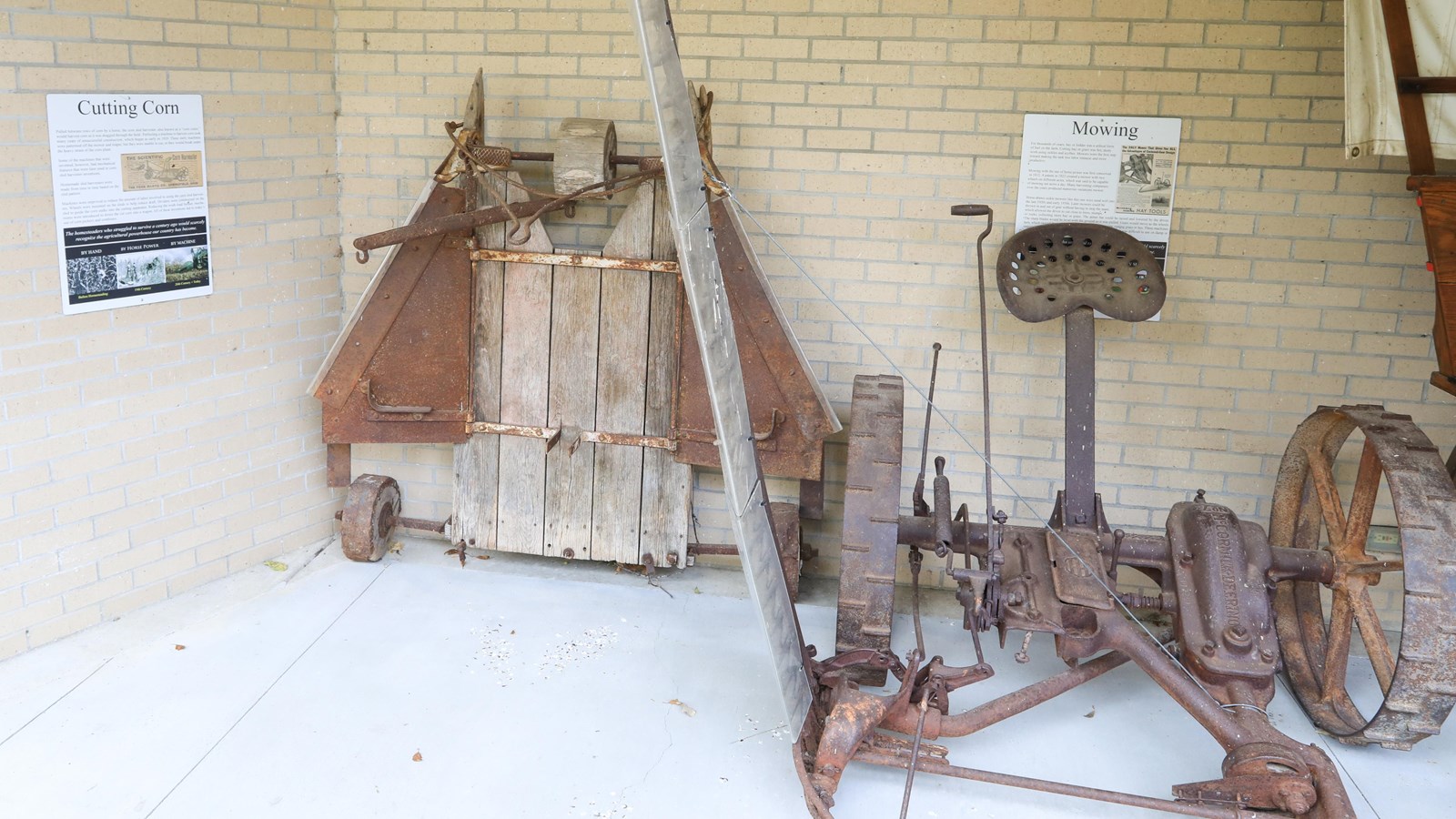 Bladed wood and metal farm equipment against a wall in front of informational panels.