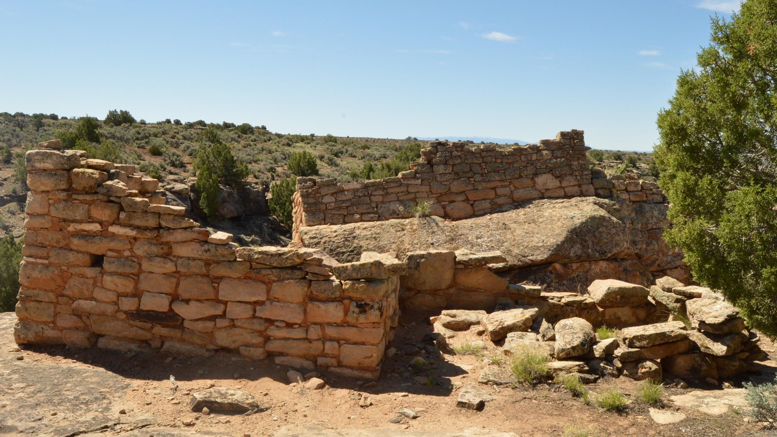 remains of stone structures on sandstone, one structure on a tilted boulder