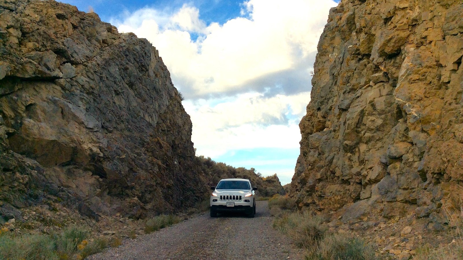 Rock cut out blue sky jeep on gravel road
