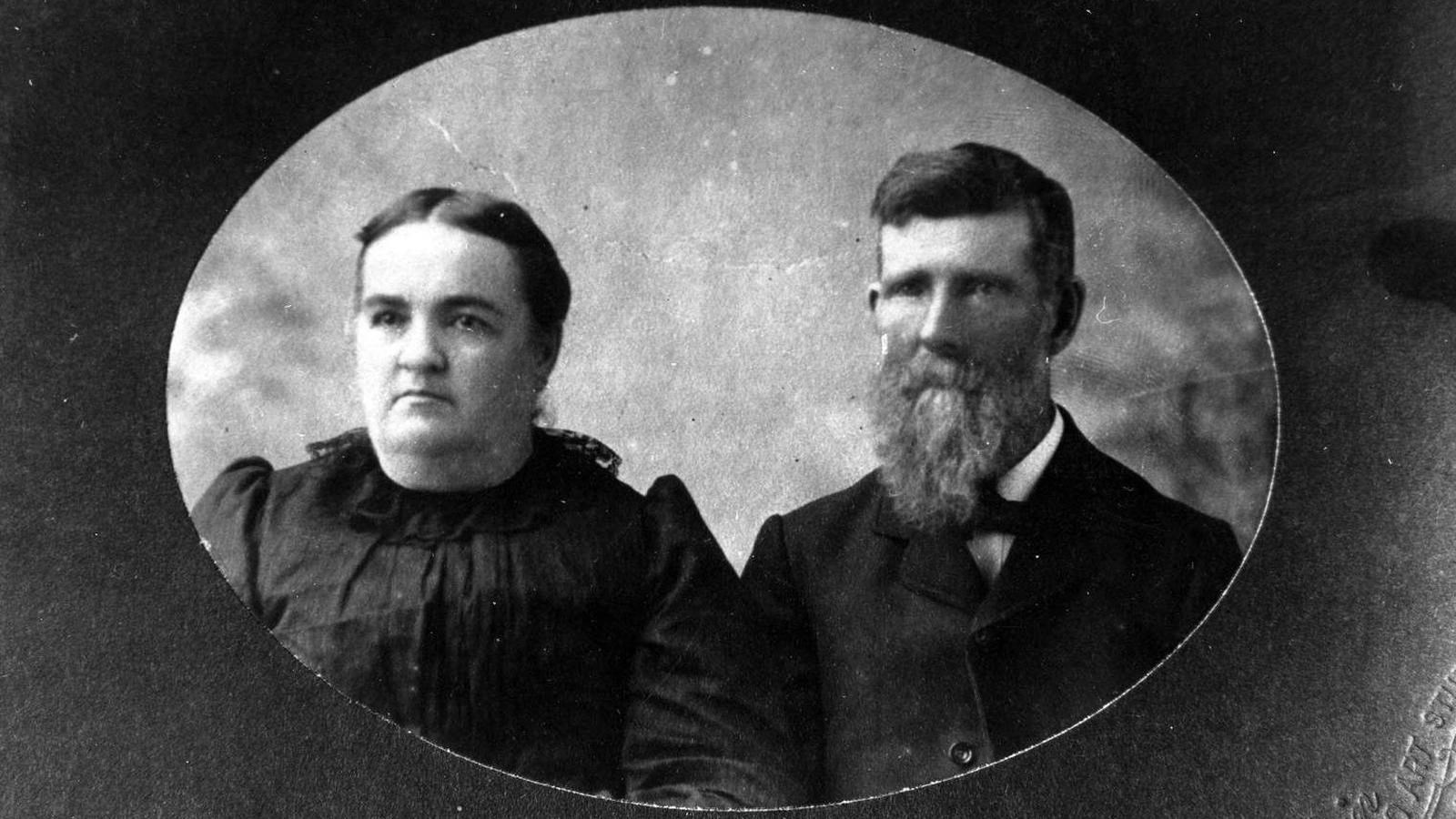 A framed portrait photo depicts a plump woman and bearded man in 1880s dress.