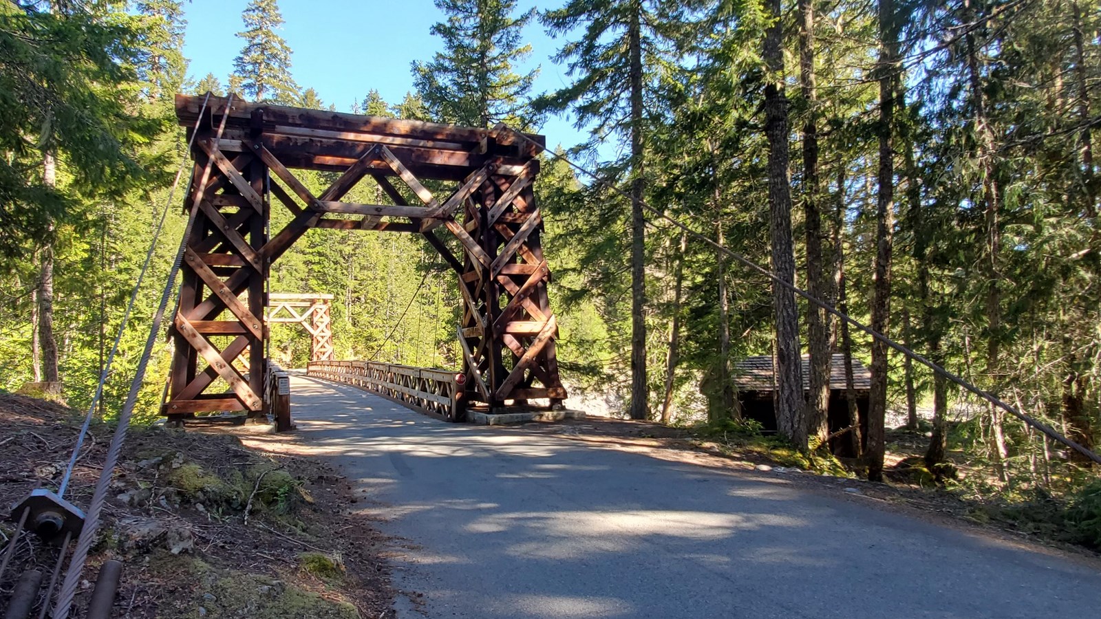 Wooden suspension bridge with steel cable supports crosses over the Nisqually river.