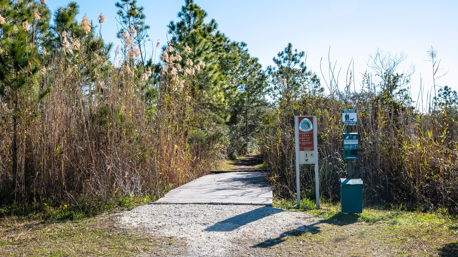 A sign for the Florida Trail stands in front of a grassy path.