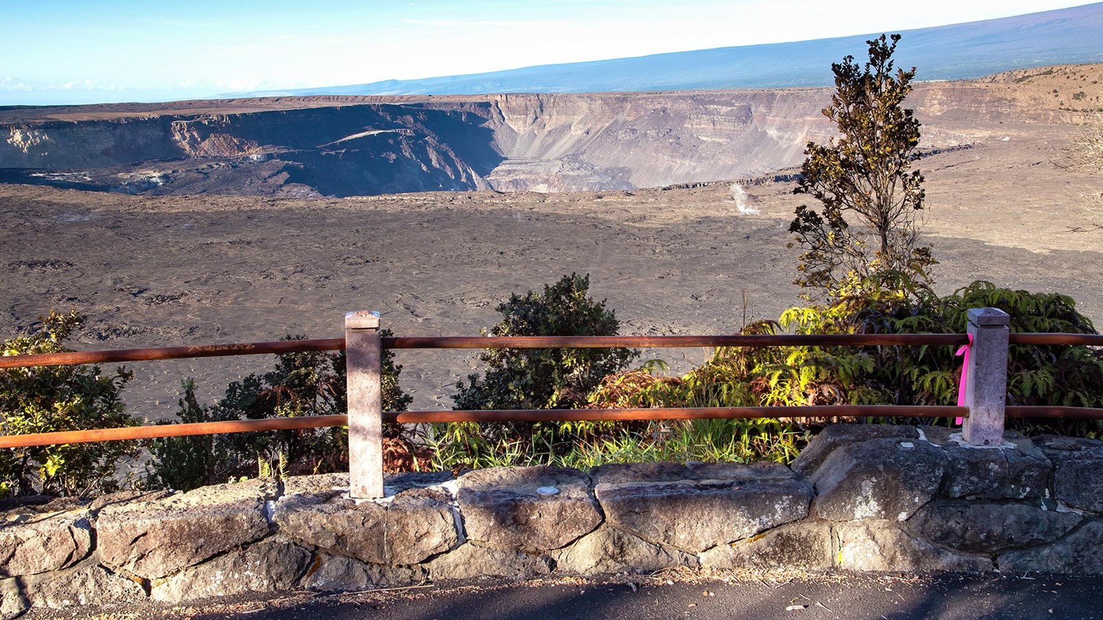 A volcanic caldera from behind an overlook fence
