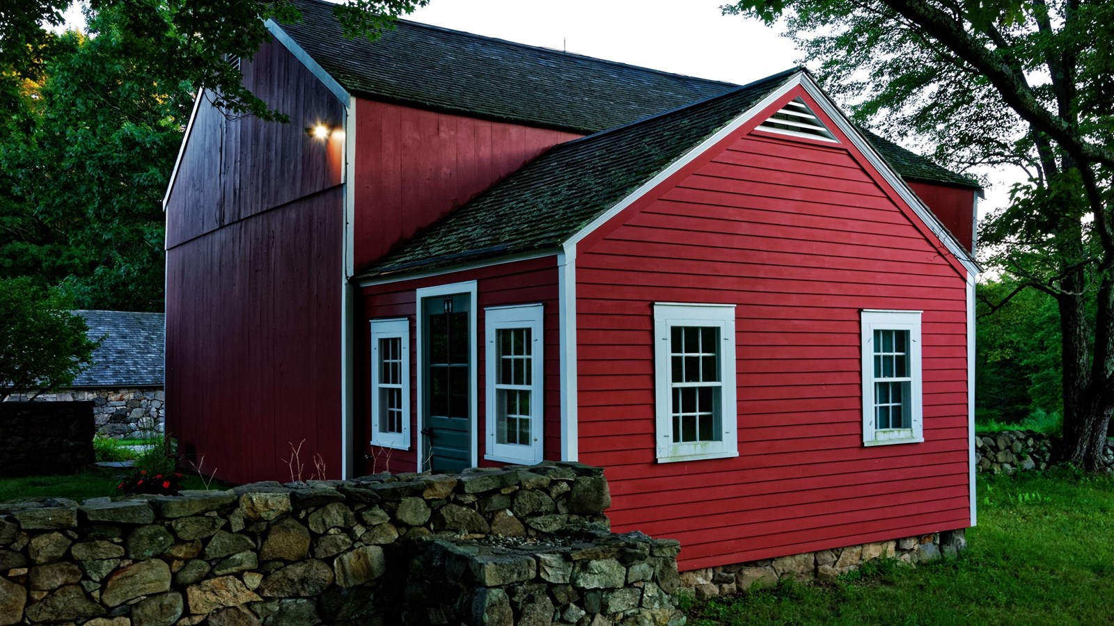 A red building at dusk with a green door and white trim.