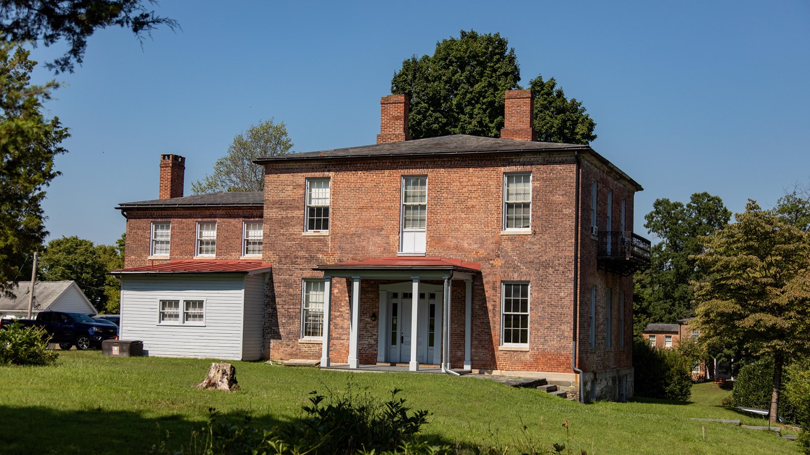 A two-story brick house with three chimneys, with 16 visible windows and a front porch.