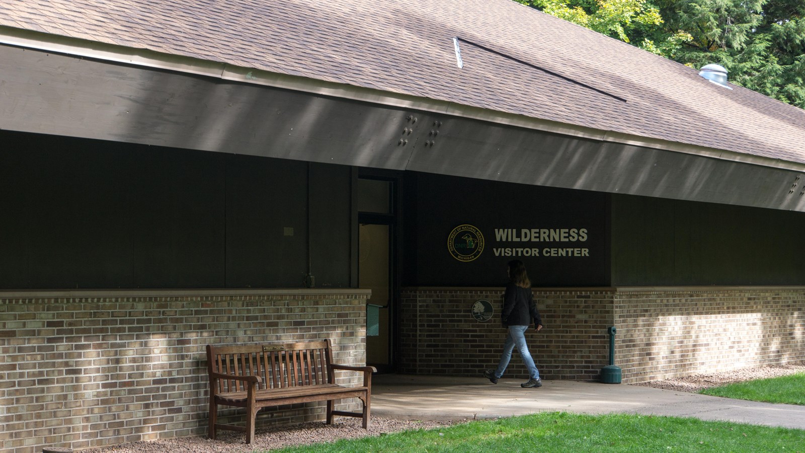 brick and wood building with steep asphalt shingled roof. A sign reads Wilderness Visitor Center